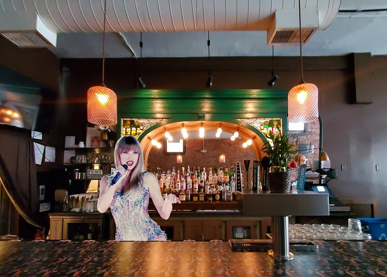 girl holding a microphone behind a bar with a mirror and a green wall