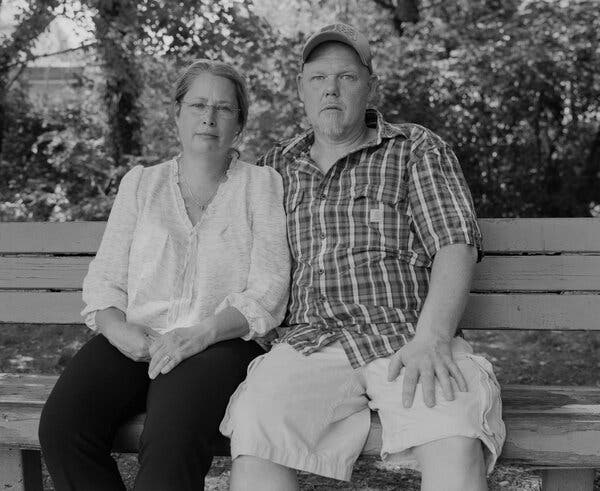 A black-and-white photograph of Jessica and Scott Smith sitting on a bench outside.