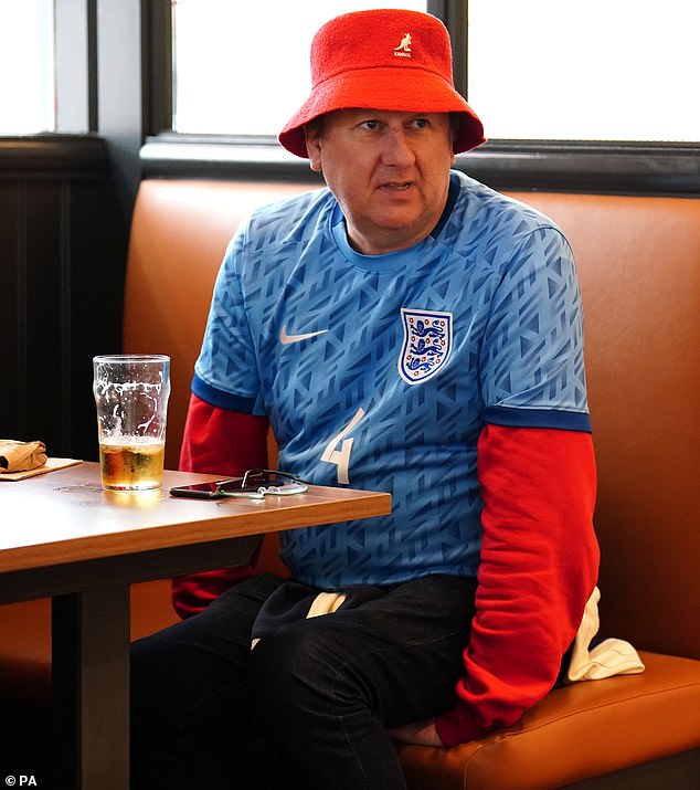 A fan in an England shirt and red bucket hat enjoys a pint ahead of the match at 12pm UK time