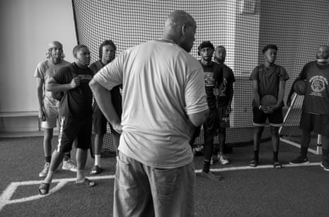 Man speaking with young men at a basketball practice. 