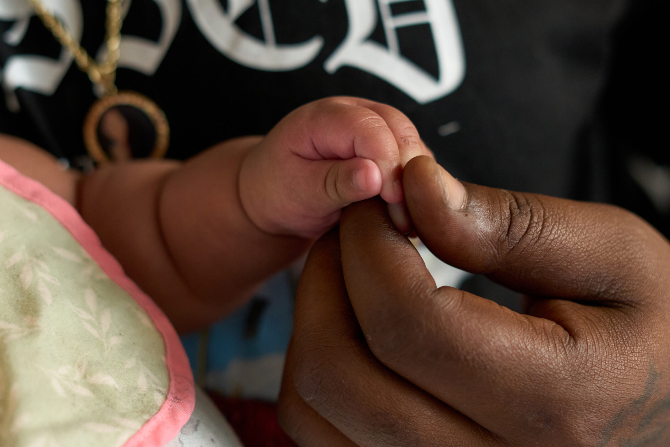 A close-up of two hands -- that of a man, the father, and his baby daughter. 