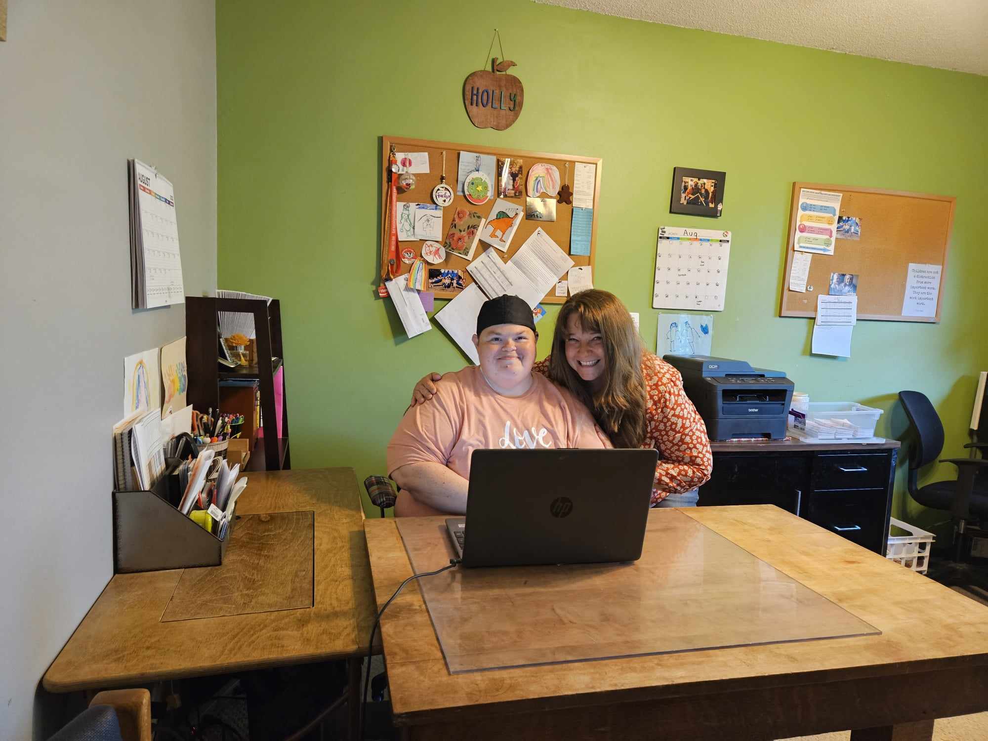 Holly Denman & Kristin Holman-Steffel pose for a picture together at Holly's desk.