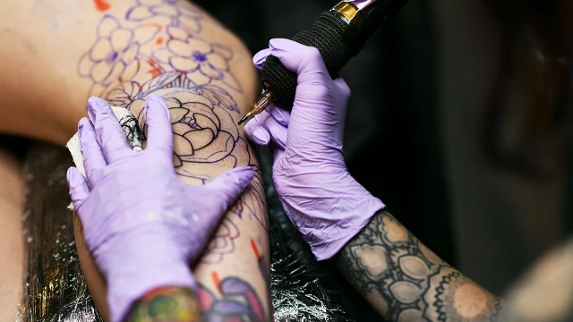 A tattoo artist inks a client's calf in Denver. (Hyoung Chang/The Denver Post)