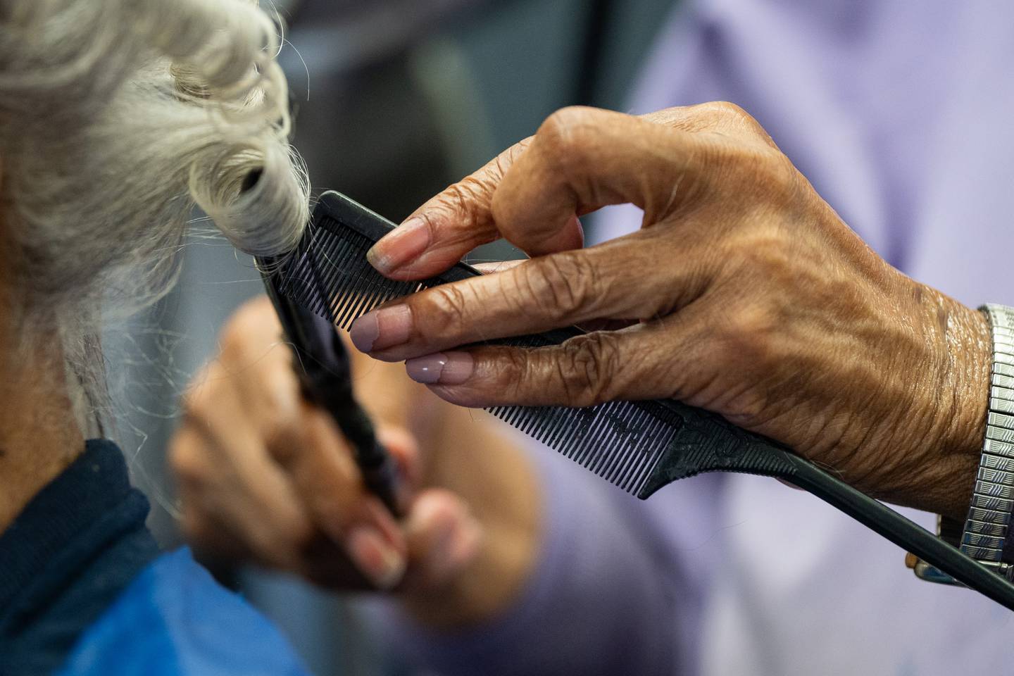 A close-up of Elizabeth Johnson's hands as she gives a customer a press and curl.