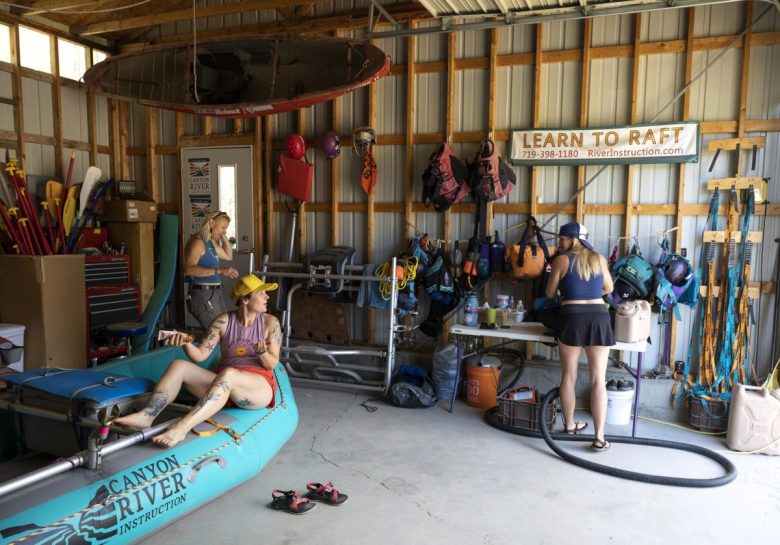 Three woman prepare raft gear inside a warehouse