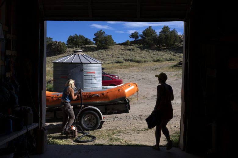 A woman inflates an orange raft sitting on a trailer