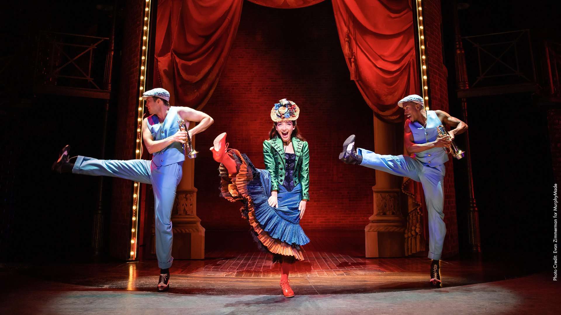 Three figures in old fashioned dress kick up their heels in a dance