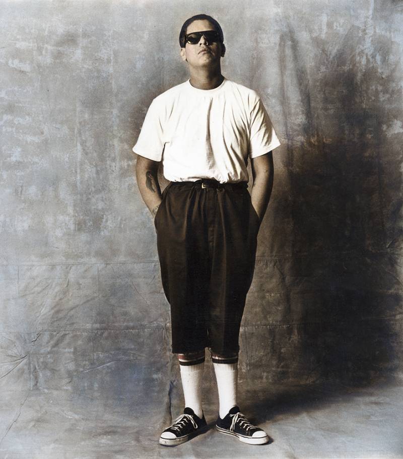 A person wearing sunglasses stands with his hands in his pockets
