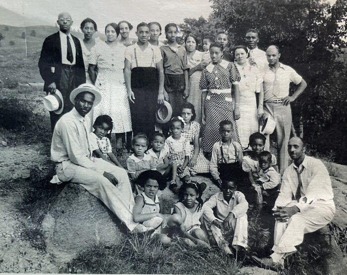 More than two dozen people pose for a photo. The photo looks older and is black and white.