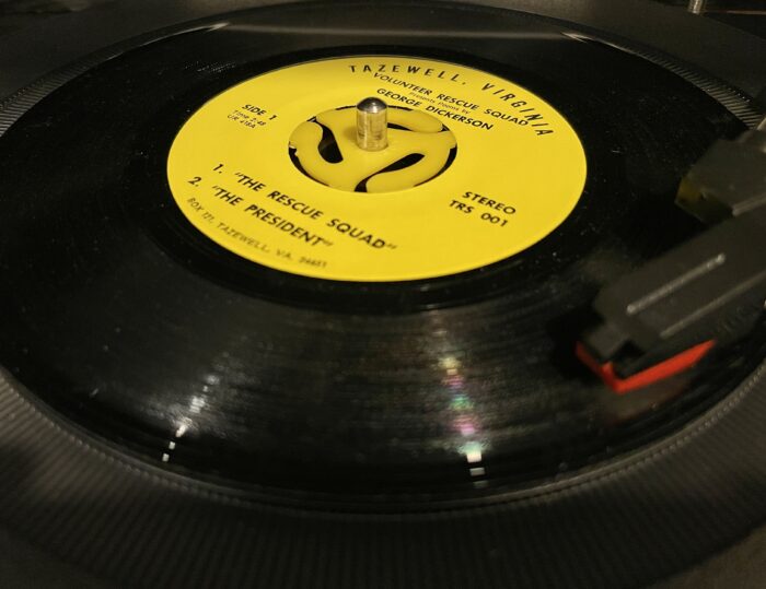 A record is shown in a record player. It reads 