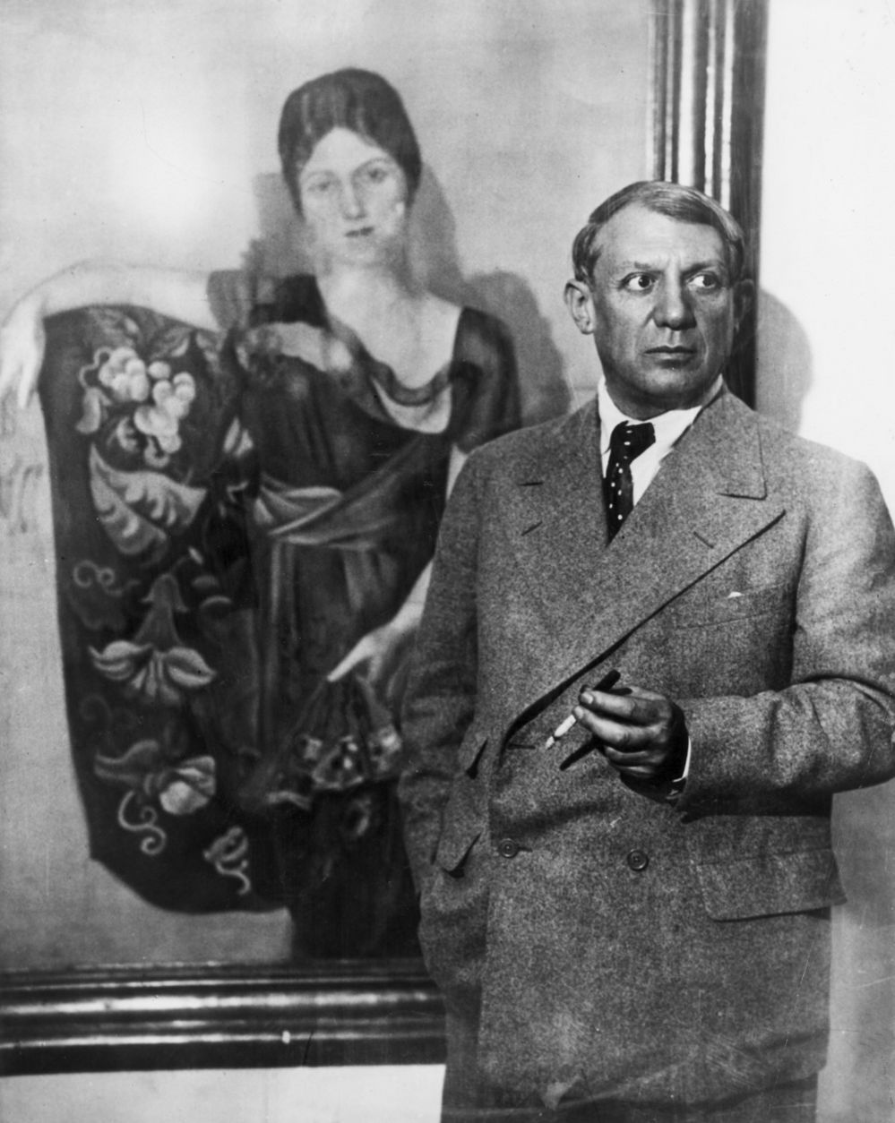 Picasso stands in front of the portrait he created of his wife Olga Khokhlova