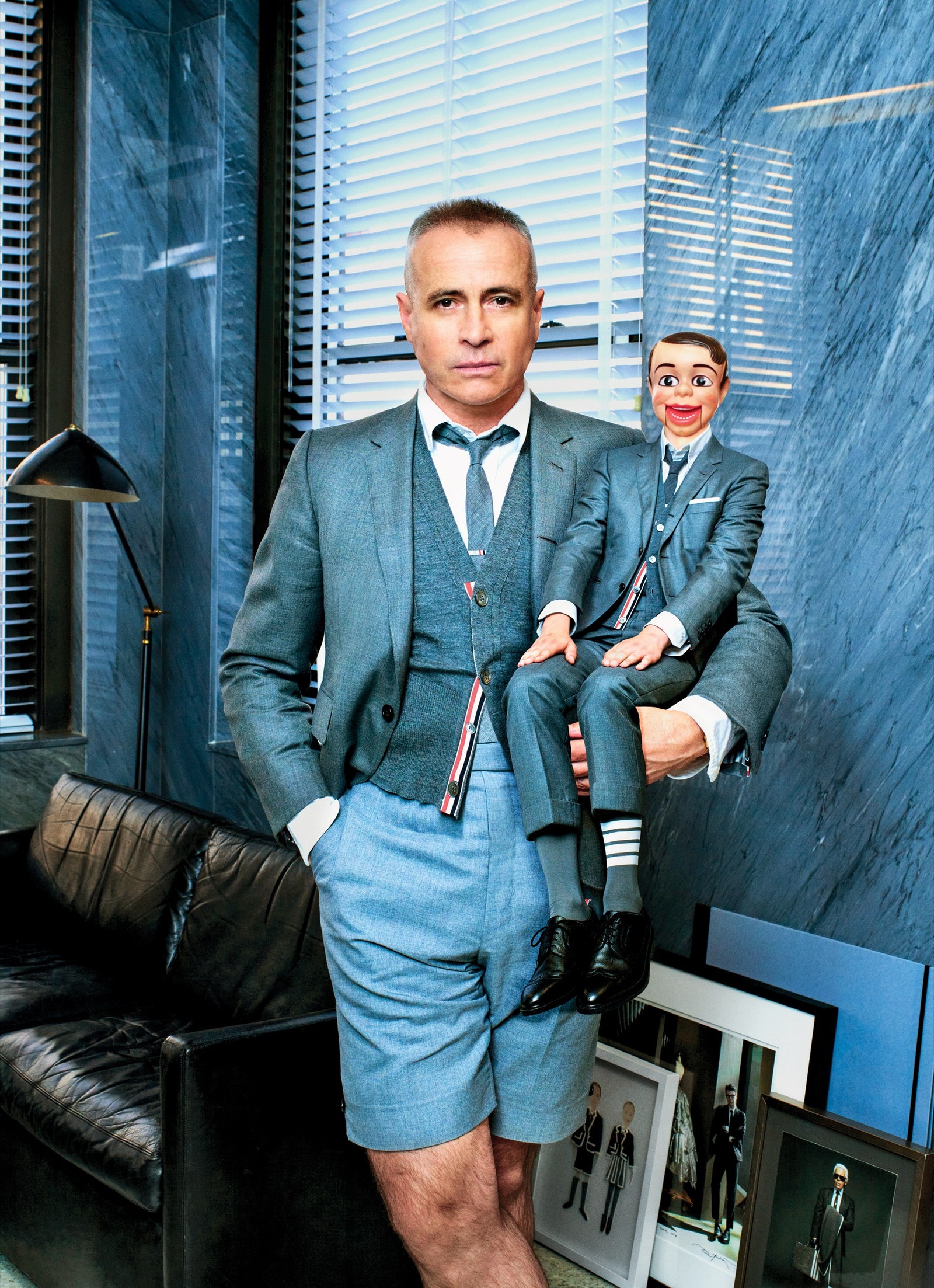Thom Browne holding a ventriloquist's dummy. Both wear similar grey suits.