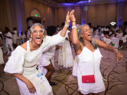 Two women dancing at a white party