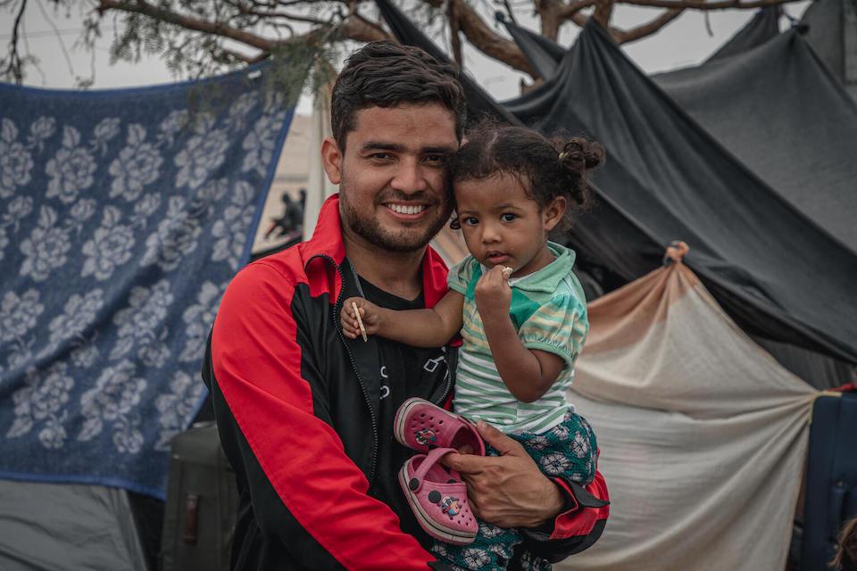 A father holds his child at a UNICEF-supported camp for migrating families from Venezuela who are stuck at the border between Chile and Peru.