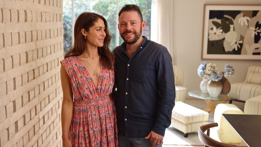 Georgia Ezra and Richie Morris stand beside a feature wall inside a completed renovation on 