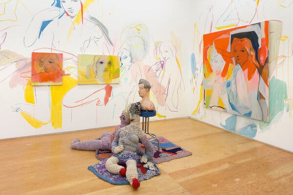 A gallery wall features murals, which have  been drawn directly into it, and three paintings of female figures in red and yellow hues; on the floor are two crochet figurative sculptures and a bust on a pedestal.