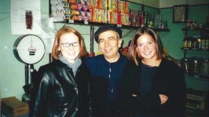 Susan Edwards Groves and Alice Green Brown with store owner Bruno. Behind them are a scale and shelves with products.