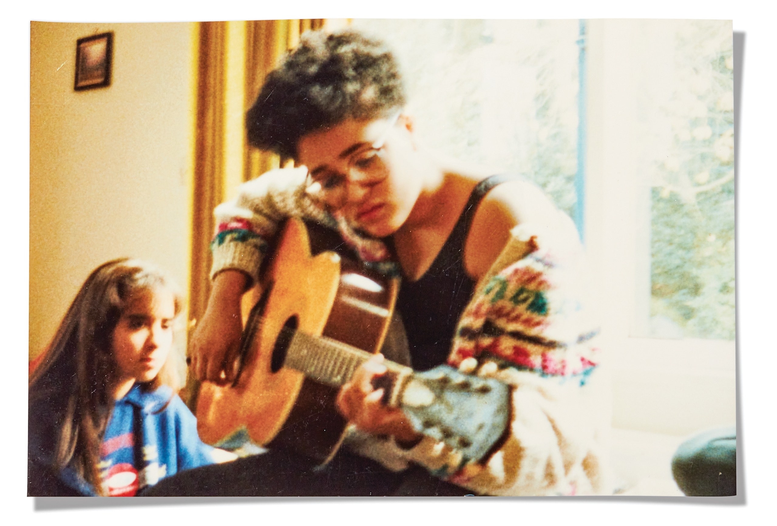 A scan of a photograph of Zadie Smith in her youth holding a guitar.