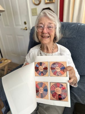 Kathryn Mooney Wall holds up a photo of several quilt squares, including one with her name on it, from a nearly century old Friendship Quilt.