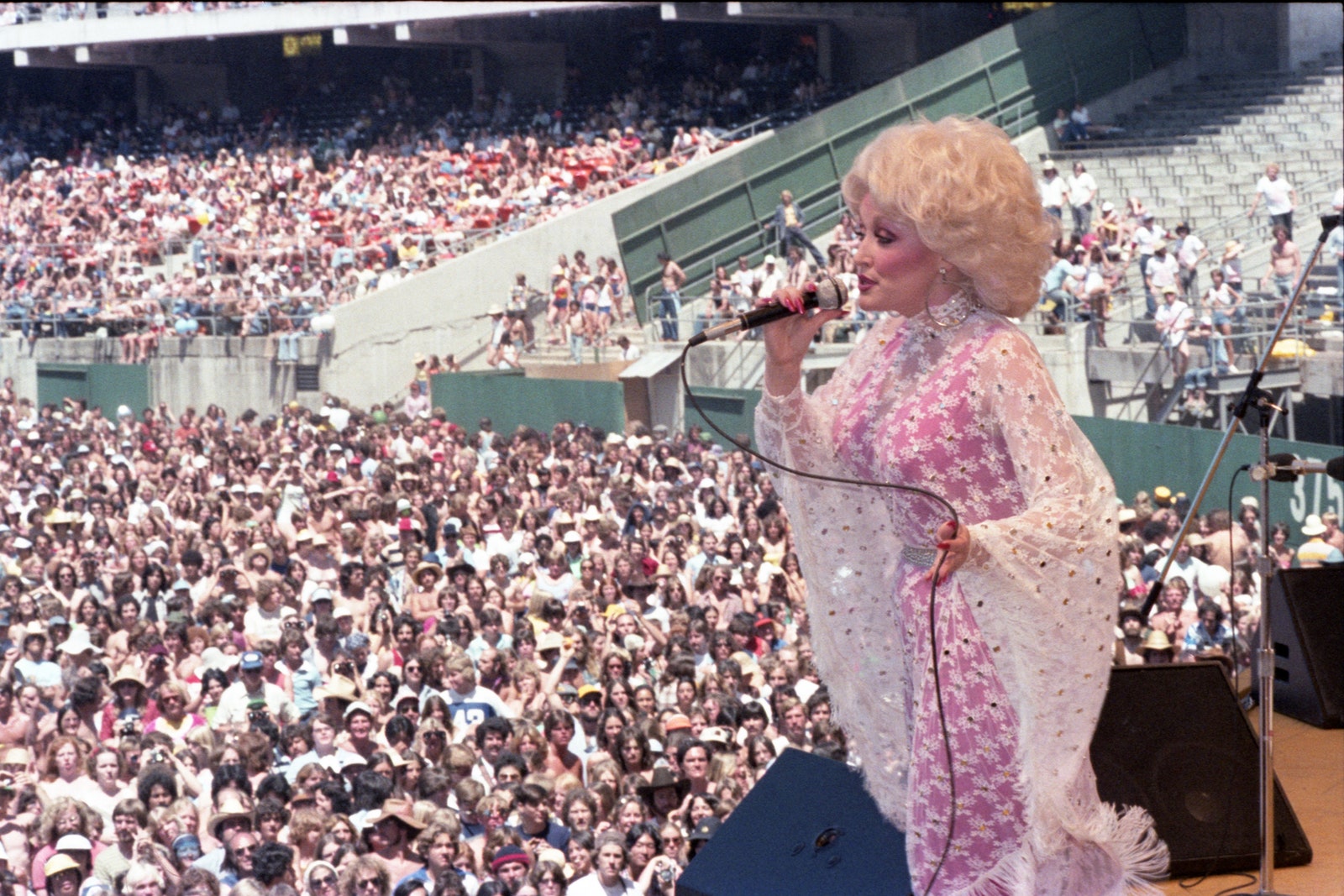 Dolly Parton performing at a packed outdoor concert.