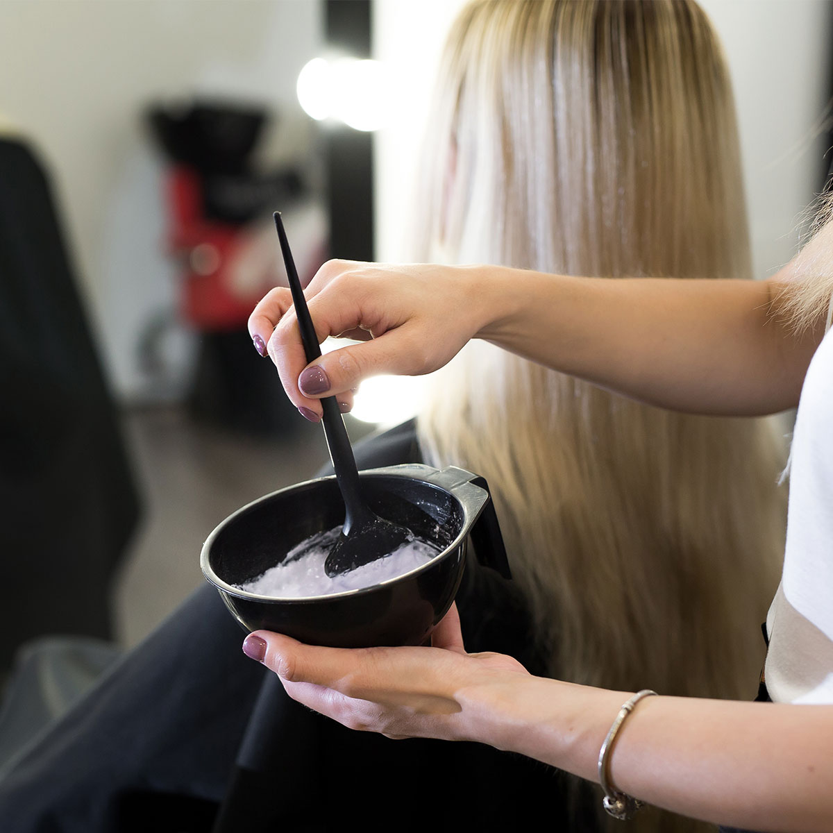 hair stylist mixing hair dye black bowl salon blonde hair client