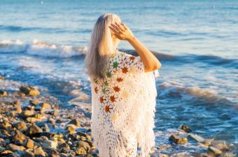 woman wearing a shawl looking at the sea waves