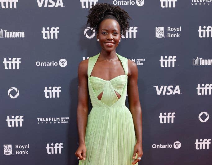 Lupita Nyong'o poses on the red carpet at the Toronto International Film Festival, wearing a stylish, floor-length gown with cut-out details