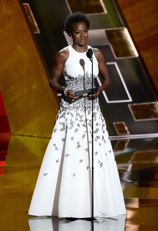 Viola Davis in a white gown on stage at the 2015 emmy awards